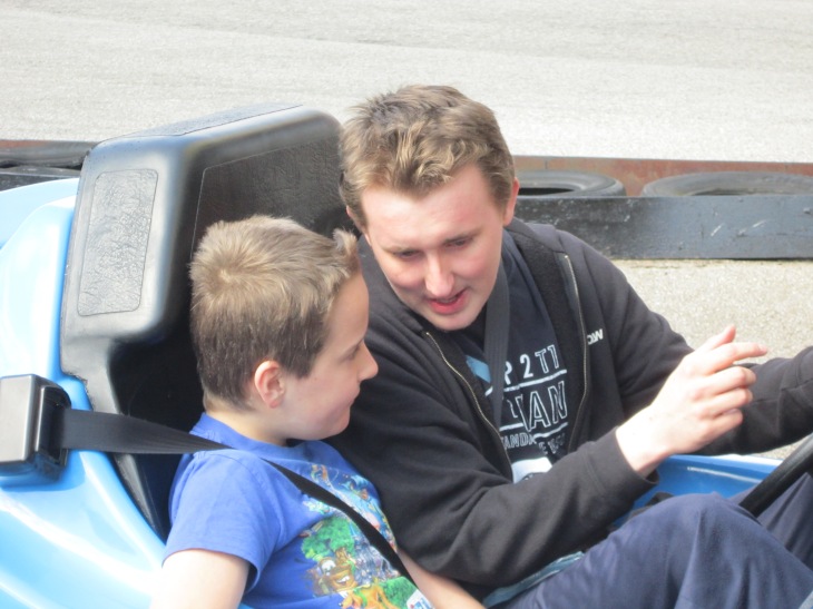 Adam and his big brother sat in a Go Kart.