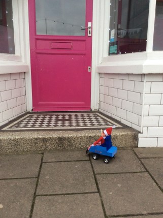 Toy Elf in powered wheelchair looking up a step to an icecream shop.