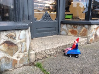 Toy Elf in powered wheelchair sat outside a bakery due to a step to the doorway.