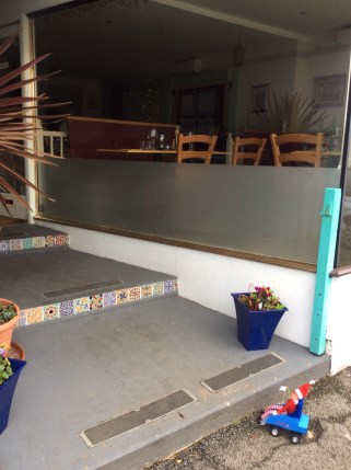 Toy Elf in toy powered wheelchair unable to access a restaurant due to three long steps.