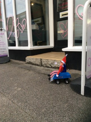 Toy Elf in powered wheelchair unable to access a hairdresser's due to a large step.