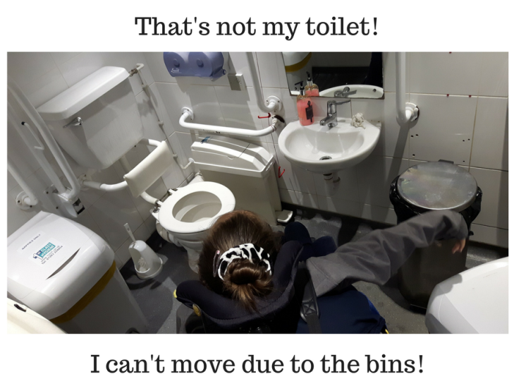 Photo taken from above looking down at the top of a girl's head. She is inside a disabled toilet and is using a wheelchair. Her chair cannot turn in the room due to small size and three bins. Text says, That's not my toilet! I can't move due to the bins!